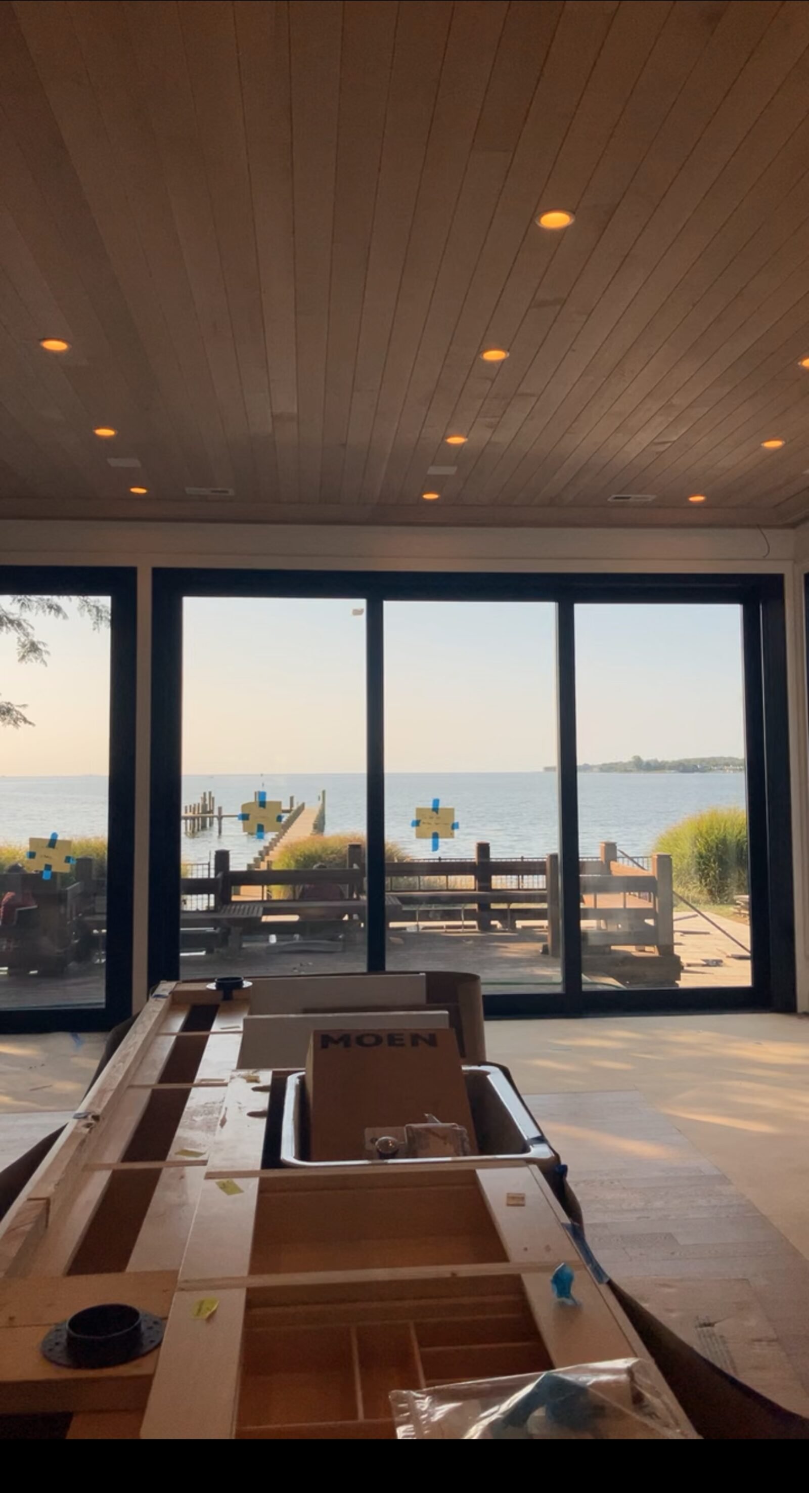 Waterfront great room with wood ceiling, recessed lighting, and glass wall to the dock